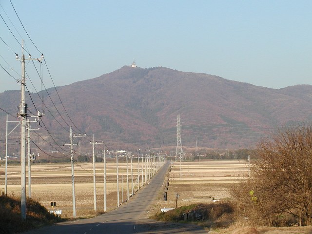 真っすぐ続く1本道の先に、ほんのり赤く色づいた宝鏡山が見える写真