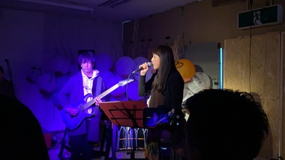 ギターの演奏を行っている男性とマイクを持って歌を歌っている女性の写真