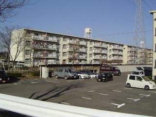 白い外観の4階建てひがし谷田川団地の写真