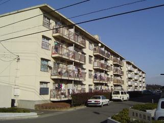 ベージュ色の壁で4階建ての駒形団地1号棟と2号棟のバルコニー側を左斜めから撮影した写真