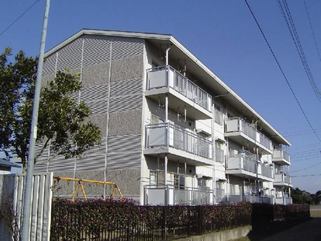 敷地内に遊具が設置された3階建ての大砂住宅を左斜めから撮影した写真