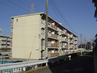 白い外観の4階建てひがし谷田川団地を道路側から写した写真