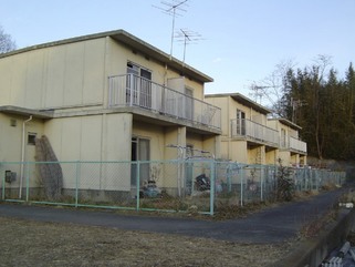 3棟建ち並んでいる2階建ての北条日向団地のフェンスで囲まれた敷地内を左斜めから撮影した写真