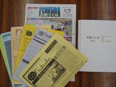 木目の机の上に、外国語版や日本語版、そして点字版のつくば市広報誌が並んでいる写真、それぞれの表紙には各国の言語で広報つくばと書かれている