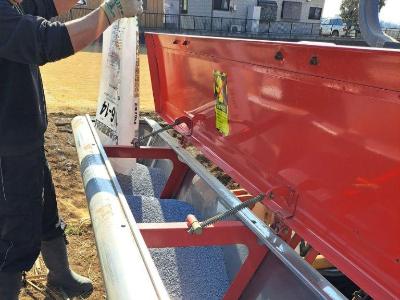 作業者が、機械に肥料を投入しています。