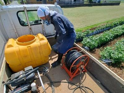作業者が、軽トラックの上で、農薬を散布する準備をしています。
