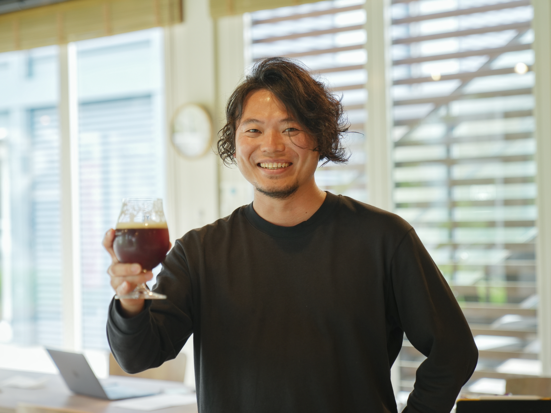 実行委員長の永田さんがグラスを片手に微笑む写真