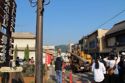 大きな重機が電柱を持ち上げたり、それを見ている人達など復旧作業中の北条商店街の写真