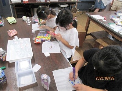 カラフルなマジックで絵を描いているプラバン工作中のこども達の写真