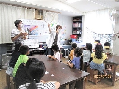 こども達が説明を聞いている実験隊の様子写真