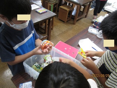 プラスチックのラベルや容器を手に取ってみているこども達の写真