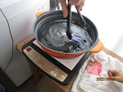 お湯の中のペットボトルをトングで動かしている写真
