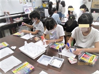 カラフルなマジックで絵を描いているプラバン工作中のこども達の写真