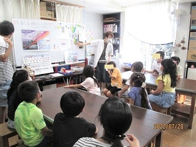 こども達が説明を聞いている実験隊の様子写真