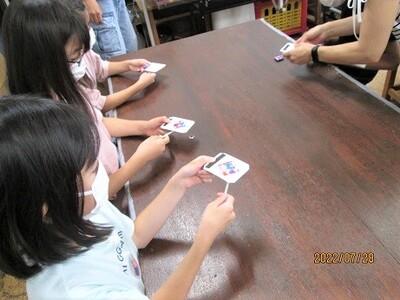こども達がカラフルな色が付いた棒付のプレートを持っている写真