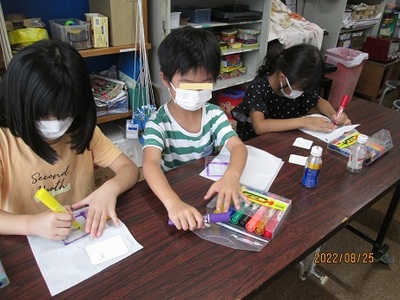 透明なプラスチックにマジックでカラフルな絵を描いているこども達の写真