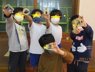 作品とポーズをとる子供たちの写真