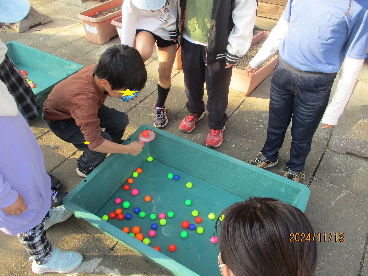 紙のポイで、スーパーボールをすくう子どもたち