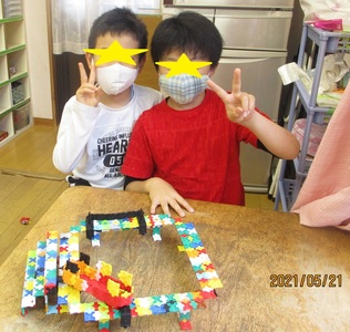 ラキューの作品と一緒にピースをしている2人の男の子の写真