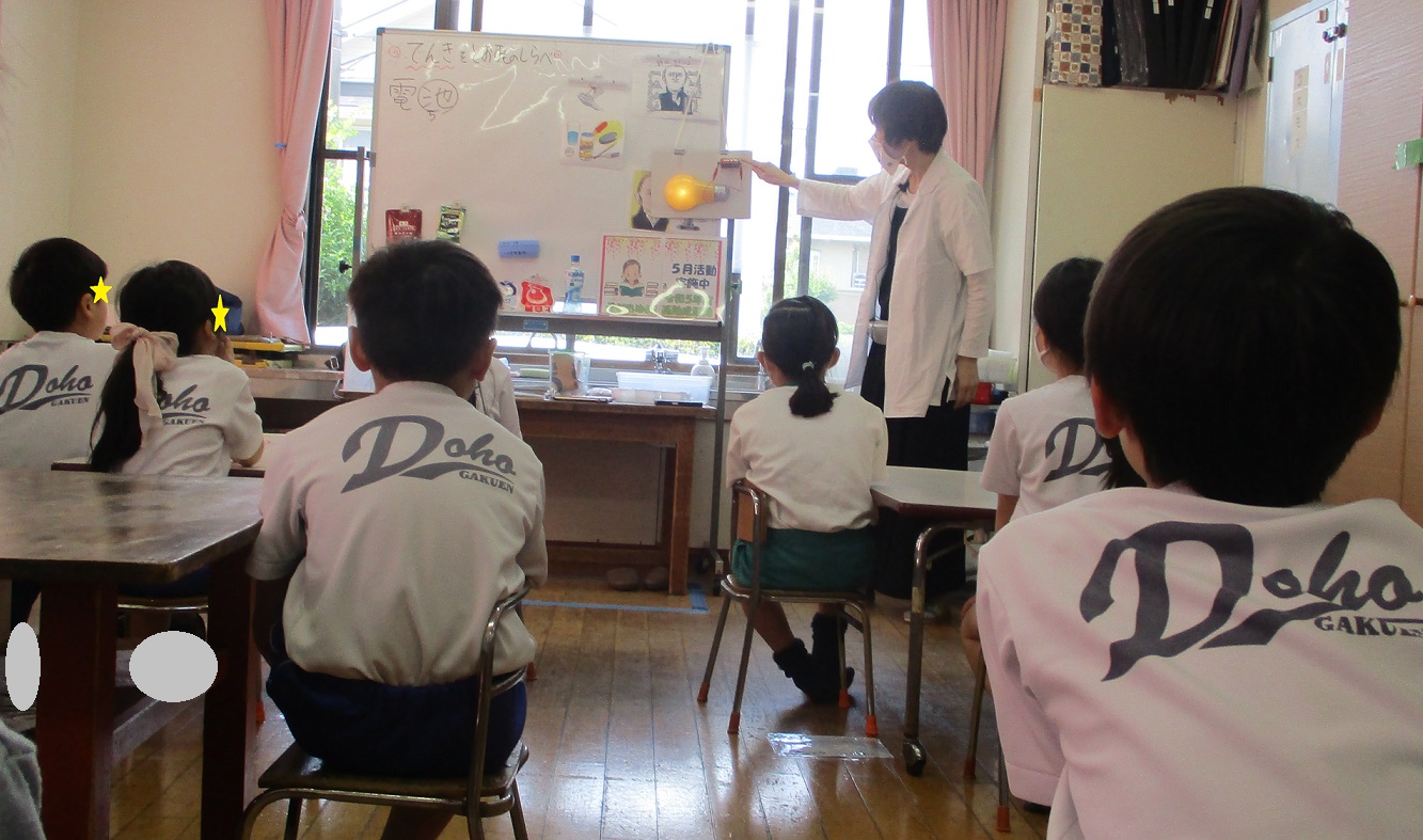 電気の流れる仕組みの説明を聞く子供たち