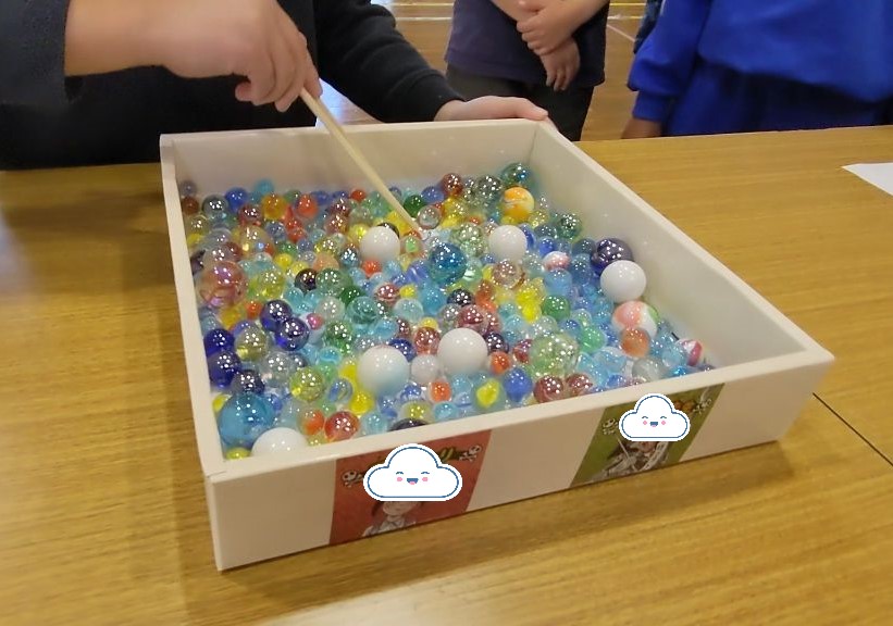 箱に入っている大中小のビー玉と割り箸