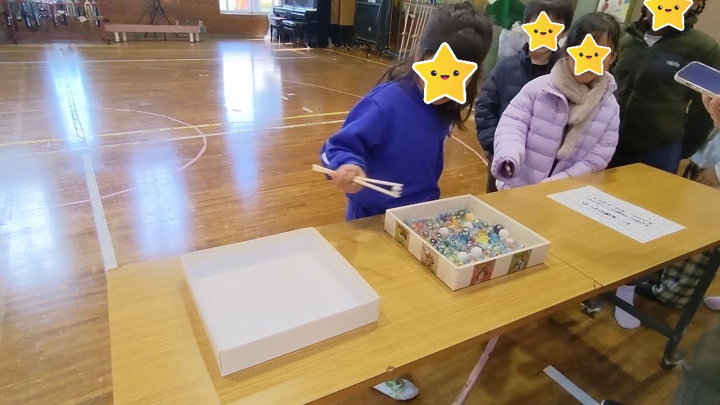 割り箸でビー玉をつまんで隣の箱に移そうとしている所