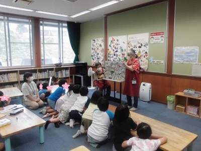 ボランティアの方の紙芝居に前のめりになるほど集中する子供たちの写真