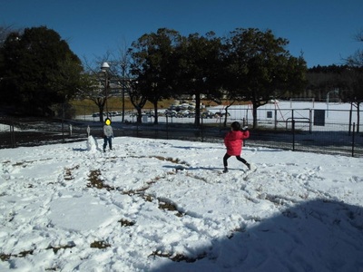 奥の方で雪合戦をしている子供の写真