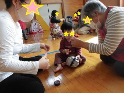くしゃくしゃになった新聞を丸めてテープを貼っている子どもの写真
