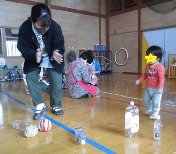 丸めた新聞紙で作ったボールでボーリング遊びをする子どもの写真