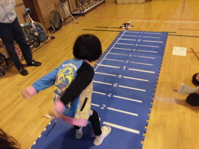計測マットに立ち大きく手を振りジャンプ寸前の子供の写真