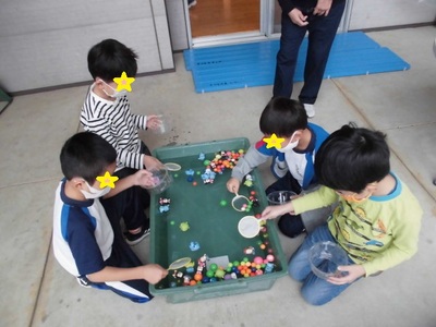 色とりどりのスーパーボールを4人の子供たちが掬っている様子の写真