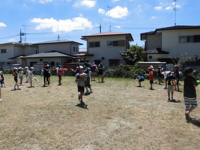 外で子どもたちが水鉄砲で遊んでいる写真