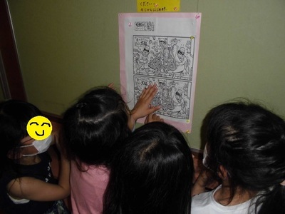 間違い探しの絵を見て、間違いを探している4人の子たち