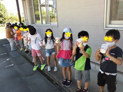 かき氷を入れるためのカップを持って順番に並んでいる子どもたちの写真