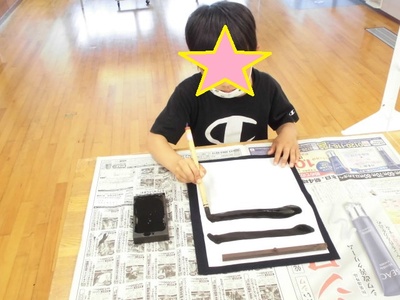 子どもが筆で一の字を書いている様子の写真