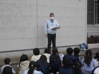 前に立っている館長先生の話を子どもたちが座って聞いている後ろ姿の写真