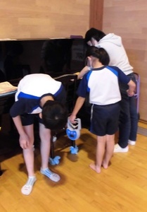 握力測定器を持った女の子が握り、男の子が測定器のメーターを確認している様子の写真
