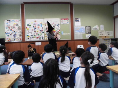 魔女の格好をした先生が、子どもたちに人形をつかって話しかけている様子