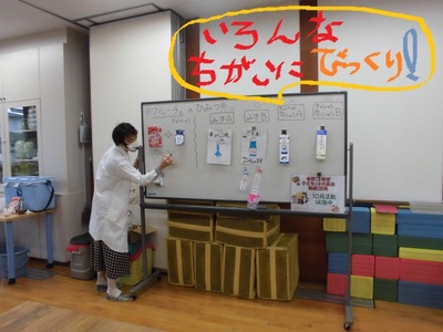 ホワイトボードに混ぜた液体のパッケージを貼り付けて説明している写真「いろんなちがいにびっくり!」