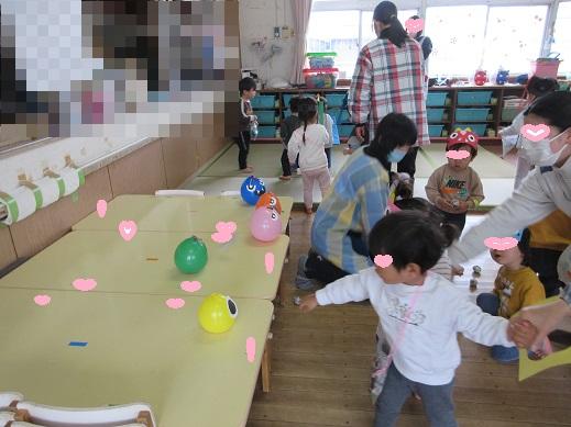 風船で作った起き上がりこぶしに向かい、新聞紙の豆を投げる、ばら組もも組の子どもたち