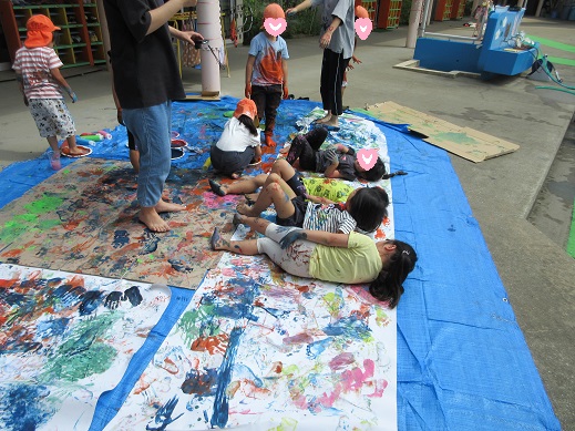 大きな紙の上に絵の具を付けて寝転び楽しむ様子