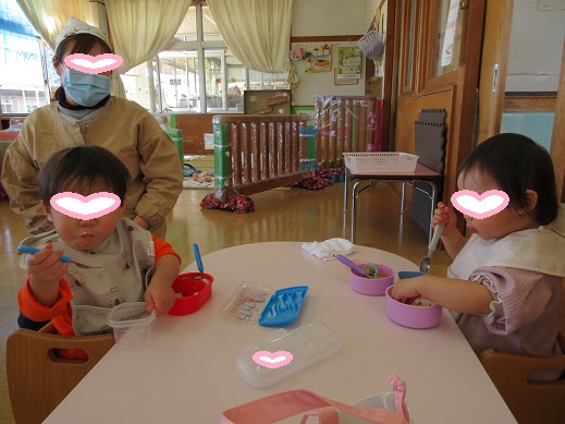 手掴みやスプーンで、お弁当を食べるちゅうりっぷ組の子どもたち