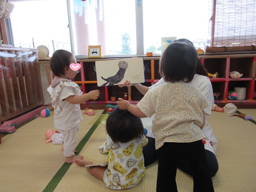 絵本のらっこを見て真似ようとする0歳児
