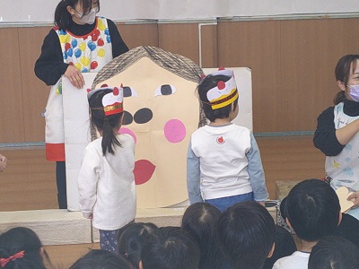 大きなおかめの顔に、目、鼻、口と貼り付けているところ
