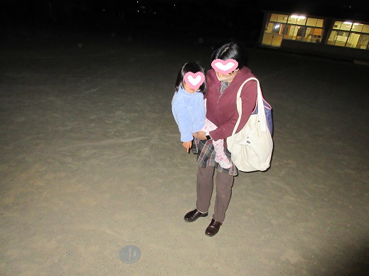 お母さんの抱っこで帰る途中に地面の蓋を指さす2歳児