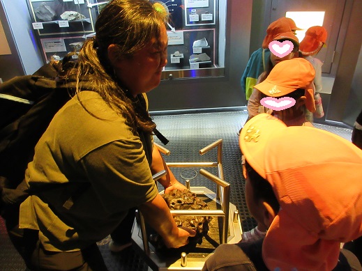 隕石を持ち上げようとする保育士