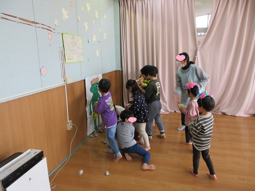 泣き虫オニに新聞紙の豆を当てるこどもたち