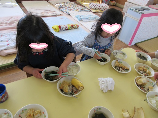 お箸で食べようと一生懸命に澄まし汁の具を掴もうとしています。