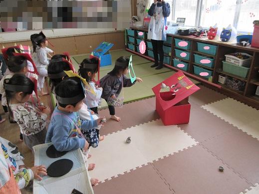 鬼の的に向かい豆に見立てた新聞紙を投げ入れる、ばら組もも組の子どもたち
